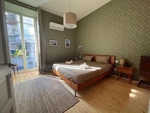 Une chambre à coucher avec un lit, une fenêtre, une table de chevet et un climatiseur fixé au mur.
