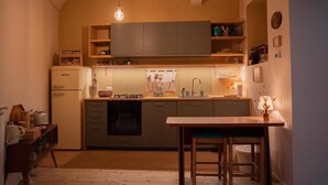 A compact kitchen with a built-in oven, a sink, and a wooden dining table. - Casa Vayu-Rooms and Garden-Rione Sanità (Naples)