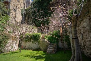 A stone staircase leading up to a building, surrounded by greenery and flowering trees. - Casa Vayu-Rooms and Garden-Rione Sanità (Naples)