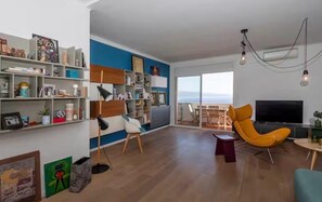 Ein modernes Wohnzimmer mit einer Couch, einem Fernseher und einem Bücherregal.
