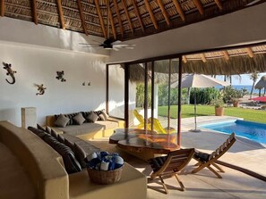 Ein moderner Innenraum mit einer Couch, einem Esstisch und einem Pool im Freien.