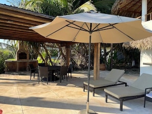 An outdoor patio with a grill, lounge chairs, and a large umbrella. - Casa Fuente Ocean Villa (Santa María Colotepec)