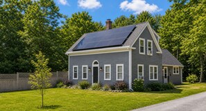 A two-story house with a solar panel roof, a front porch, and a well-maintained lawn. - FIFA World Cup Stay • Whole House • 21 Miles to Gillette Stadium (Hanover)
