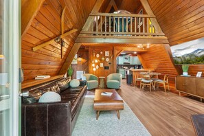 Ein gemütlicher, holzgetäfelter Innenraum mit Schlafzimmer im oberen Bereich, Essbereich und Küche.
