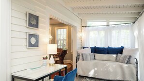 Ein Zimmer mit einem Bett, einem Tisch, Stühlen und gerahmten Kunstwerken an der Wand.