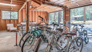 Ein überdachter Fahrradstellplatz mit mehreren Fahrrädern, Holzwänden und einem Fenster mit Blick ins Freie.