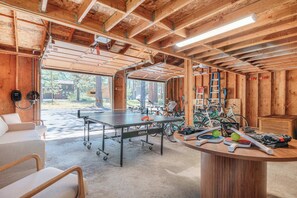 A wooden interior with a ping pong table, bicycles, and a ping pong paddle. - Pine & Powder - SHARC, Hot Tub, Bikes, EV Charger (Sunriver)