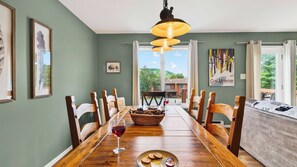 A dining area with a wooden table, chairs, a chandelier, and artwork on the walls. - Lies by Avantstay Indoor Heated Pool + Game Lounge Pool Table + Foosball (North Creek)