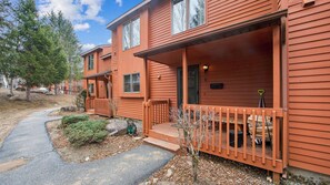 A two-story wooden building with a porch, a welcome sign, and a small garden area. - Lies by Avantstay Indoor Heated Pool + Game Lounge Pool Table + Foosball (North Creek)