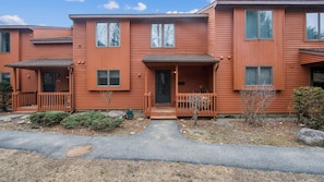 A row of red wooden townhouses with front porches, a driveway, and a small garden area. - Lies by Avantstay Indoor Heated Pool + Game Lounge Pool Table + Foosball (North Creek)
