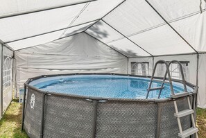 Ein Aufstellpool mit einer Leiter, umgeben von einer weißen Zelthalle.