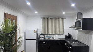 A compact kitchen with a refrigerator, microwave, toaster, and gas stove.