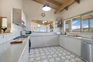 A modern kitchen with a hexagonal tile floor, stainless steel appliances, and a large window providing natural light. - Cue the Views at Seven (Clifton Springs)
