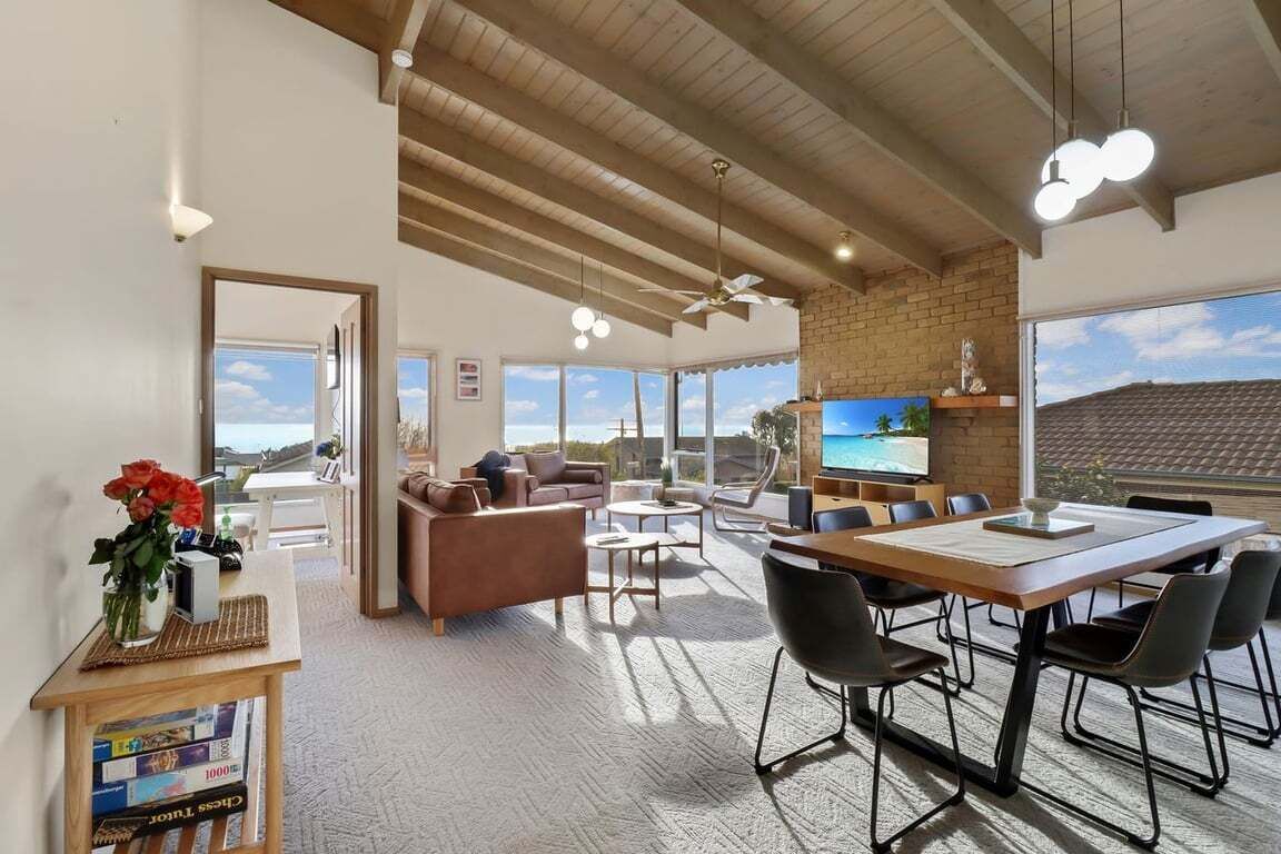 A spacious living area with a high ceiling, a dining table, and comfortable seating.