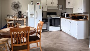 Una cocina moderna con armarios blancos, una mesa de comedor con sillas y un espejo decorativo en la pared.