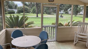 A covered porch with a table and chairs, a white rocking chair, and a 'Welcome' sign. - Shellpoint in Townsend Ga. Spacious 3-bedroom mobile home lodge fee 129. a night (Townsend)
