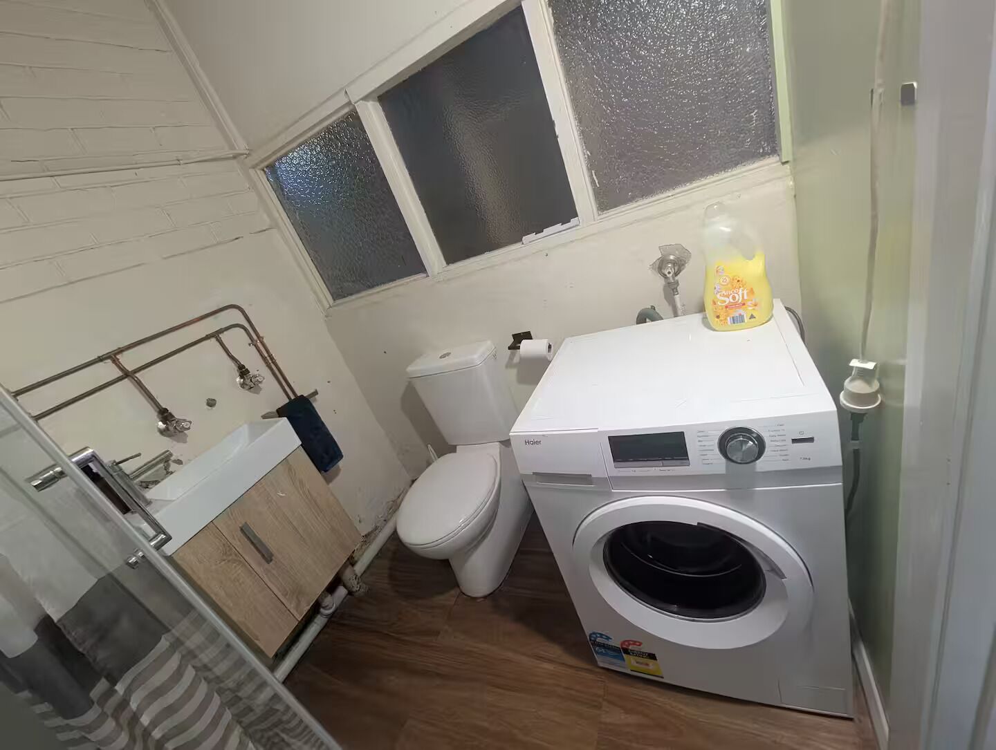 Et lille badeværelse med vaskemaskine, toilet og håndvask.