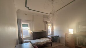 Een slaapkamer met een bed, bureau, stoel, dressoir en een kroonluchter.
