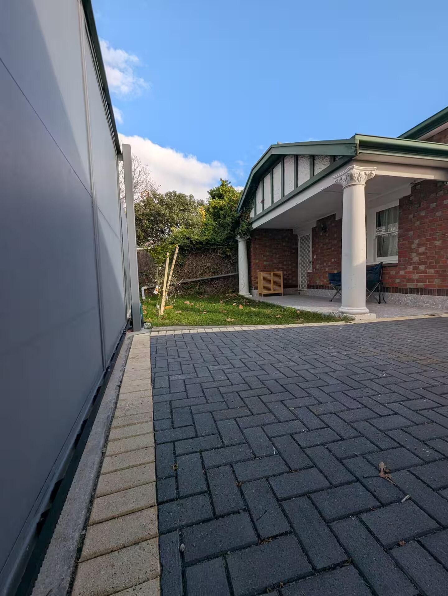 En bygning med murstensfacade, en overdækket veranda og en belagt indkørsel.