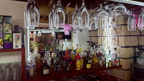 Una zona de bar con copas colgando, una variedad de botellas y platos apilados.