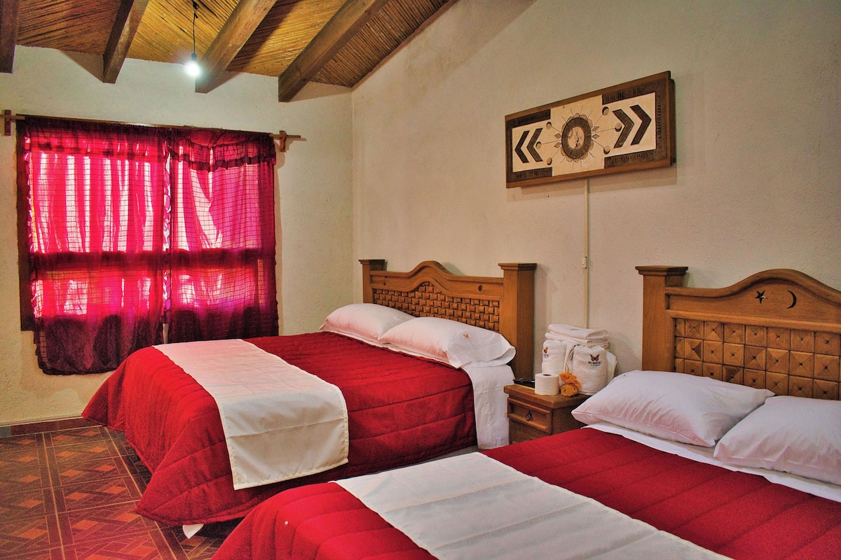Una habitación de hotel con dos camas, un cabecero de madera, una cortina roja, un reloj de pared y un cuadro enmarcado.