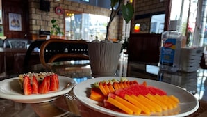 Interior de restaurante con pared de ladrillo, una planta en maceta y una mesa con platos de comida.