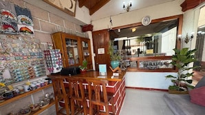 Una zona de bar con taburetes de madera, un mostrador con diversos artículos y una pared decorada con recuerdos.