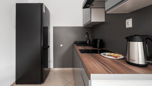 Eine moderne Küche mit einem schwarzen Kühlschrank, einer Kaffeemaschine und einem Bosch-Wasserkocher auf der Arbeitsfläche.