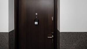 Une porte en bois sombre, dotée d’un clavier numérique, d’une sonnette et d’une poignée de porte.