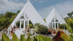 Two white triangular buildings with glass doors, surrounded by tropical plants and a clear sky. - Luxor Pyramid – Tropical Paradise in Fort Myers (Fort Myers)