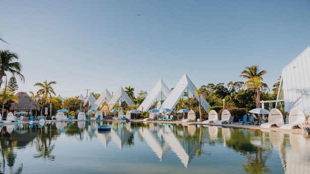 A pool area with lounge chairs and umbrellas, surrounded by palm trees and modern architecture. - Luxor Pyramid – Tropical Paradise in Fort Myers (Fort Myers)