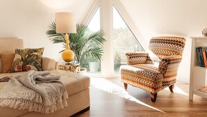 A living room with a sofa, a patterned armchair, a lamp, a potted plant, and a bookshelf. - Luxor Pyramid – Tropical Paradise in Fort Myers (Fort Myers)