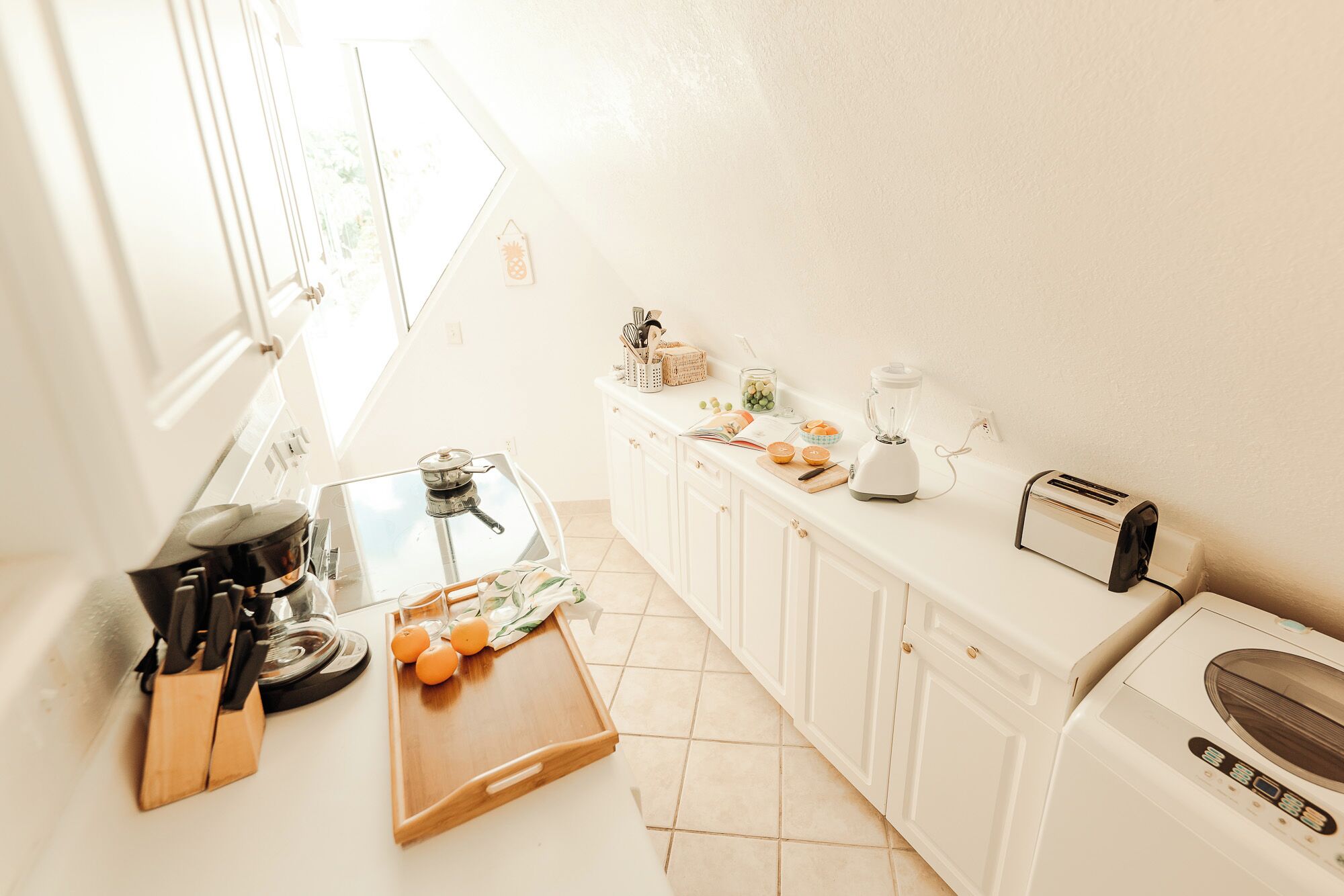 A kitchen with a stove, a blender, a toaster, and a washing machine.