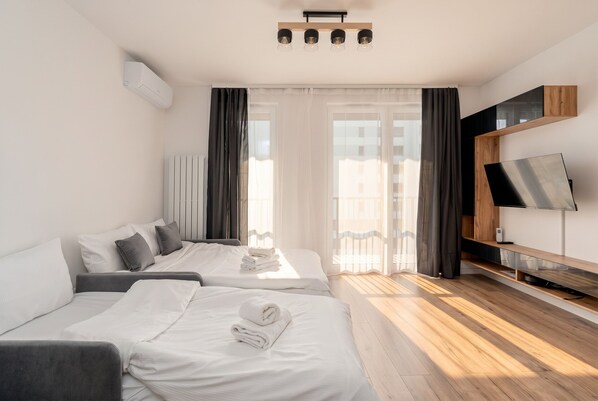 Ein Hotelzimmer mit zwei Betten, einem Fernseher und einem Balkon mit Vorhängen.