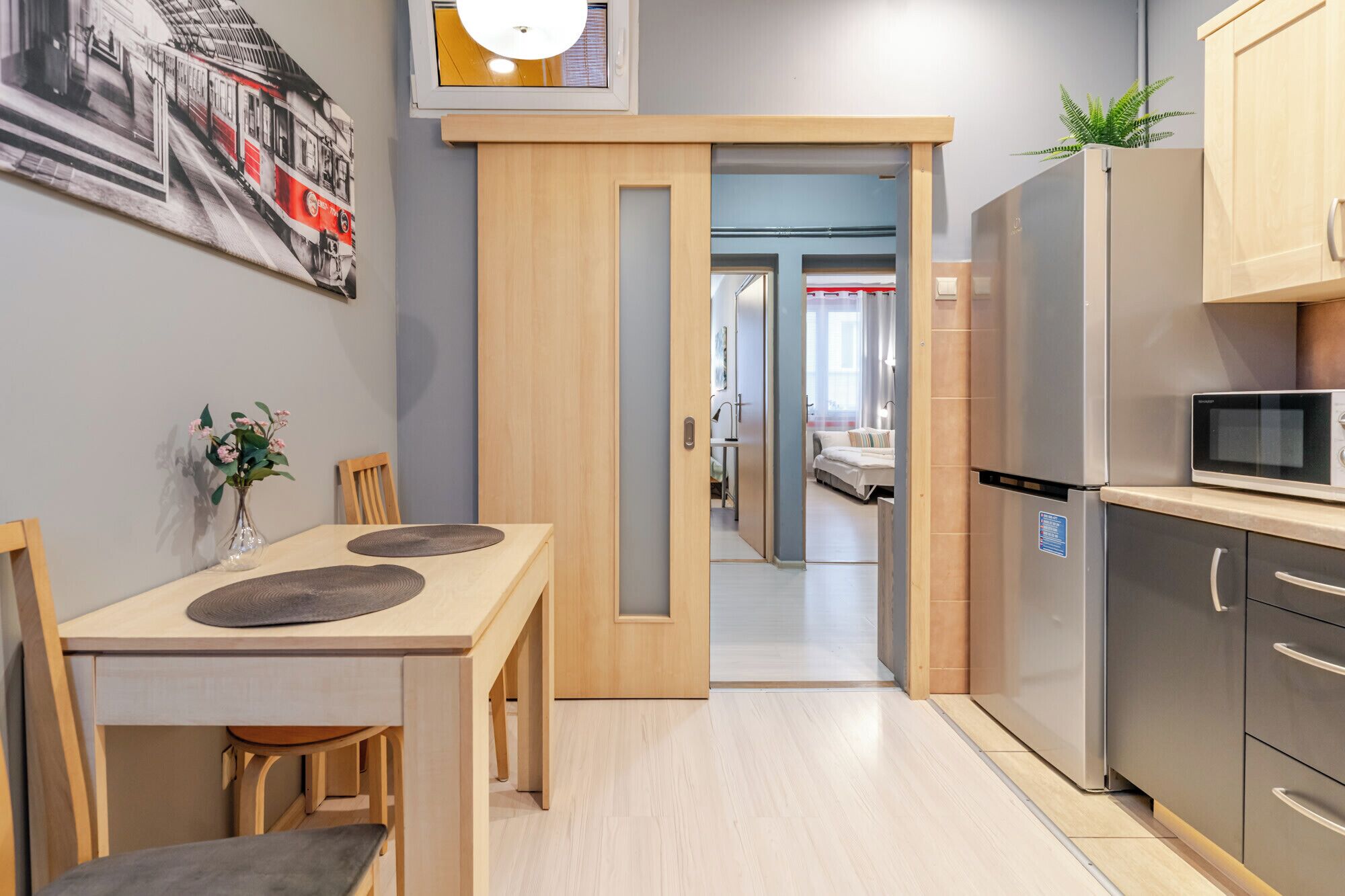 A compact kitchen with a microwave, a refrigerator, and a dining area with a table and chairs.