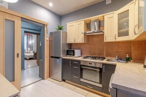 A compact kitchen with a refrigerator, microwave, stove, oven, and a sink. - Matejki Central Apartment (Katowice)