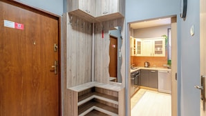Ein Hotelzimmer mit Holztür, Spiegel, eingebautem Sitzplatz und Blick in den Küchenbereich.