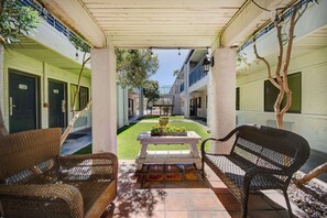 A covered outdoor area with wicker furniture, a table with flowers, and a view of the building's interior. - Adventure-Ready Stay in Tucson Pet-Friendly w/ Pool + Free Parking Onsite (Tucson)