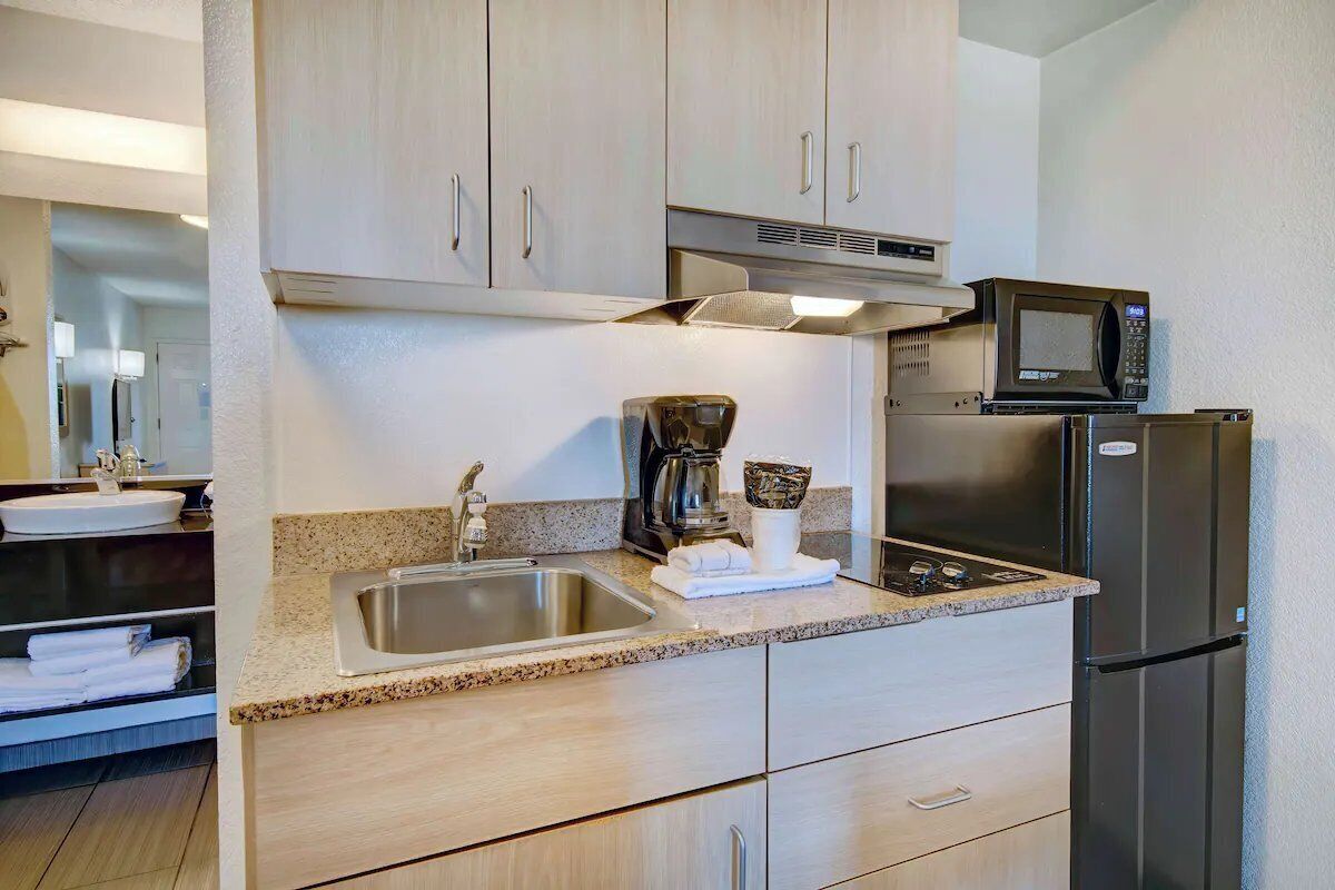 A kitchen with a stainless steel sink, a coffee maker, a microwave, and a refrigerator.