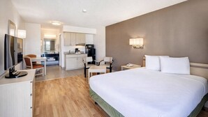 Une chambre d’hôtel équipée d’un lit, d’un bureau, de chaises, d’une télévision, d’un four à micro-ondes et d’une kitchenette.