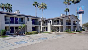 Un motel avec des bâtiments à deux étages, des palmiers et un parking aménagé pour les personnes handicapées.