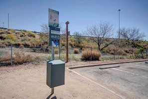 A parking lot with a fenced area, a utility box, and a signboard with instructions. - Free Parking | Pet-Allowed | 3.0 mi to Santa Cruz River Walk Path (Tucson)