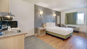 Une chambre d’hôtel avec un lit, un petit bureau avec une chaise, un lavabo et une fenêtre avec des rideaux.