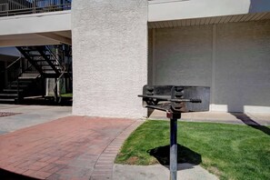 Une boîte aux lettres sur un trottoir, un chemin bordé de briques et un bâtiment à l’extérieur blanc, avec une porte de garage.