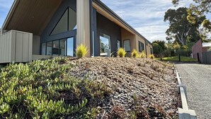 Un edificio moderno con tetto spiovente, ampie finestre e un'area verde con piante.