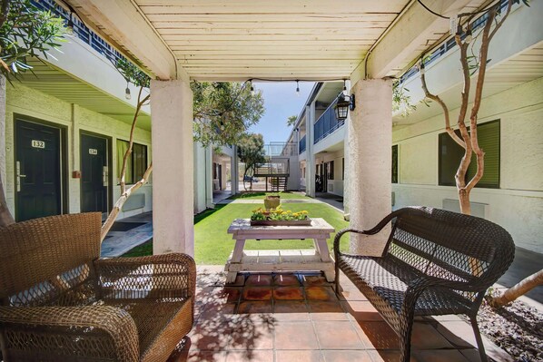 A covered outdoor area with wicker furniture, a table with flowers, and a view of the building's interior. - 2 Units | Desert Adventure Retreat | 5.1 mi to Pima Museum (Tucson)
