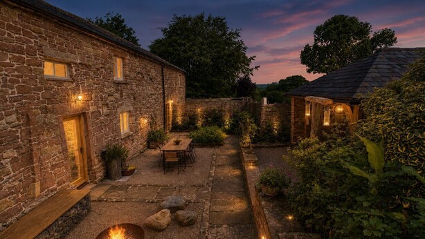 Un edificio de piedra con un brasero, asientos al aire libre y un patio bien iluminado.