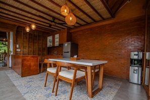 Une cuisine rustique avec une table et des chaises en bois, un réfrigérateur et un distributeur d’eau.