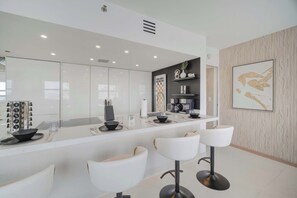 Una cocina moderna con una isla central, taburetes blancos y una obra de arte grande enmarcada en la pared.