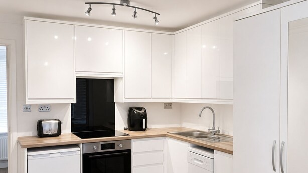 A modern kitchen with white cabinetry, a black oven, a coffee maker, and a sink. - Studio - Sleeps 2 - Wifi - Parking (Dunstable)
